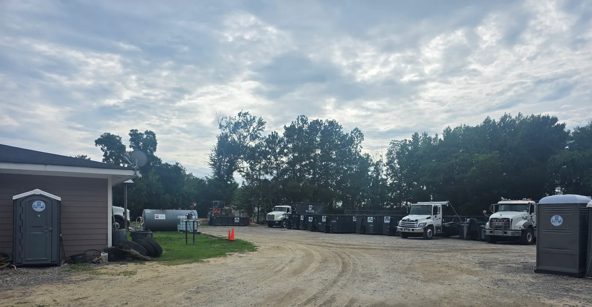 Roll-off dumpsters, trucks, and portable restrooms at the Dumpster Rental Dogs yard