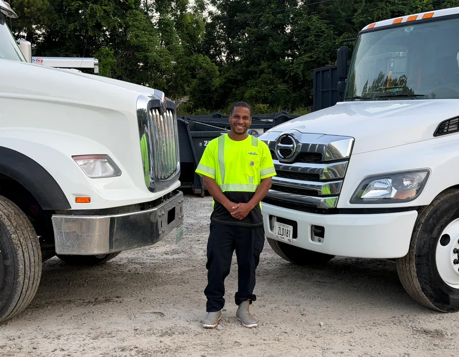 Dumpster Rental Dogs team member standing between delivery trucks